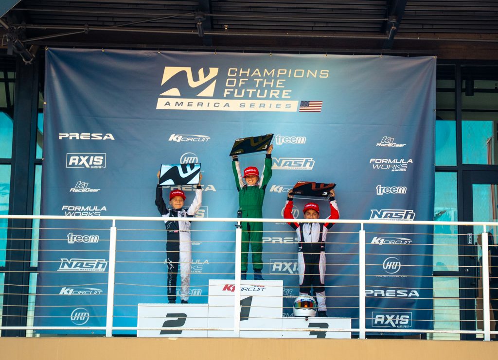 Sebastian Matyjaszczyk, Dan Duculescu, and Lucas Freitas Melo hold up awards during the Mini U10 podium ceremony for Champions of the Future America Series Round 3 at K1 Circuit