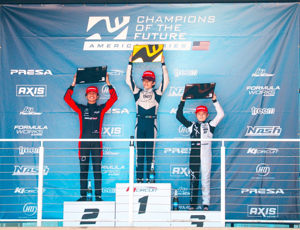 The Top 3 drivers from KA100 Junior hold up their trophies on the podium during Round 7 of Champions of the Future America