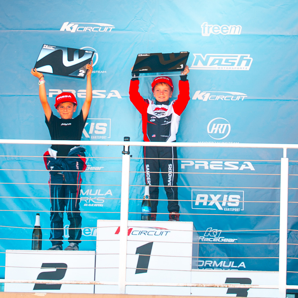 The Top 2 drivers from Mini U10 hold up their trophies on the podium